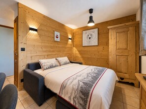 A wooden-paneled room with a bed, a chair, and a wardrobe.