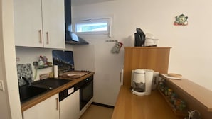 Et lille køkken med vask, komfur og kaffemaskine på bordet.