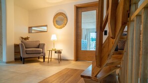 A living room with a sofa, a lamp, a mirror, and a wooden staircase. - Idyllic holiday home with far-reaching views, fireplace and secluded location. (Buchenberg)
