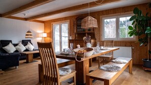 A cozy wooden interior with a dining table, chairs, and a sofa. - Idyllic holiday home with far-reaching views, fireplace and secluded location. (Buchenberg)