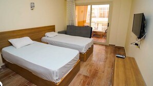 A hotel room with two single beds, a TV, and a balcony with a view. - Florenze Khamsin Hurghada Room J113 - Room 8 (Hurghada)
