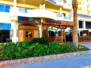 Un immeuble dont le rez-de-chaussée abrite un bar appelé « Havana Pub » et un café appelé « FREEDOM Coffee & More ».