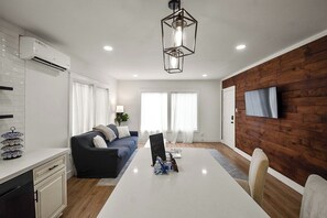 A modern kitchen with white cabinets, a dining table, and a wooden accent wall. - The Lockwood, Residence One | EaDo by the Stadiums (Houston)