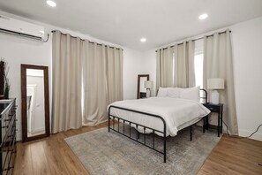 A bedroom with a bed, bedside tables, a mirror, and a window with curtains.