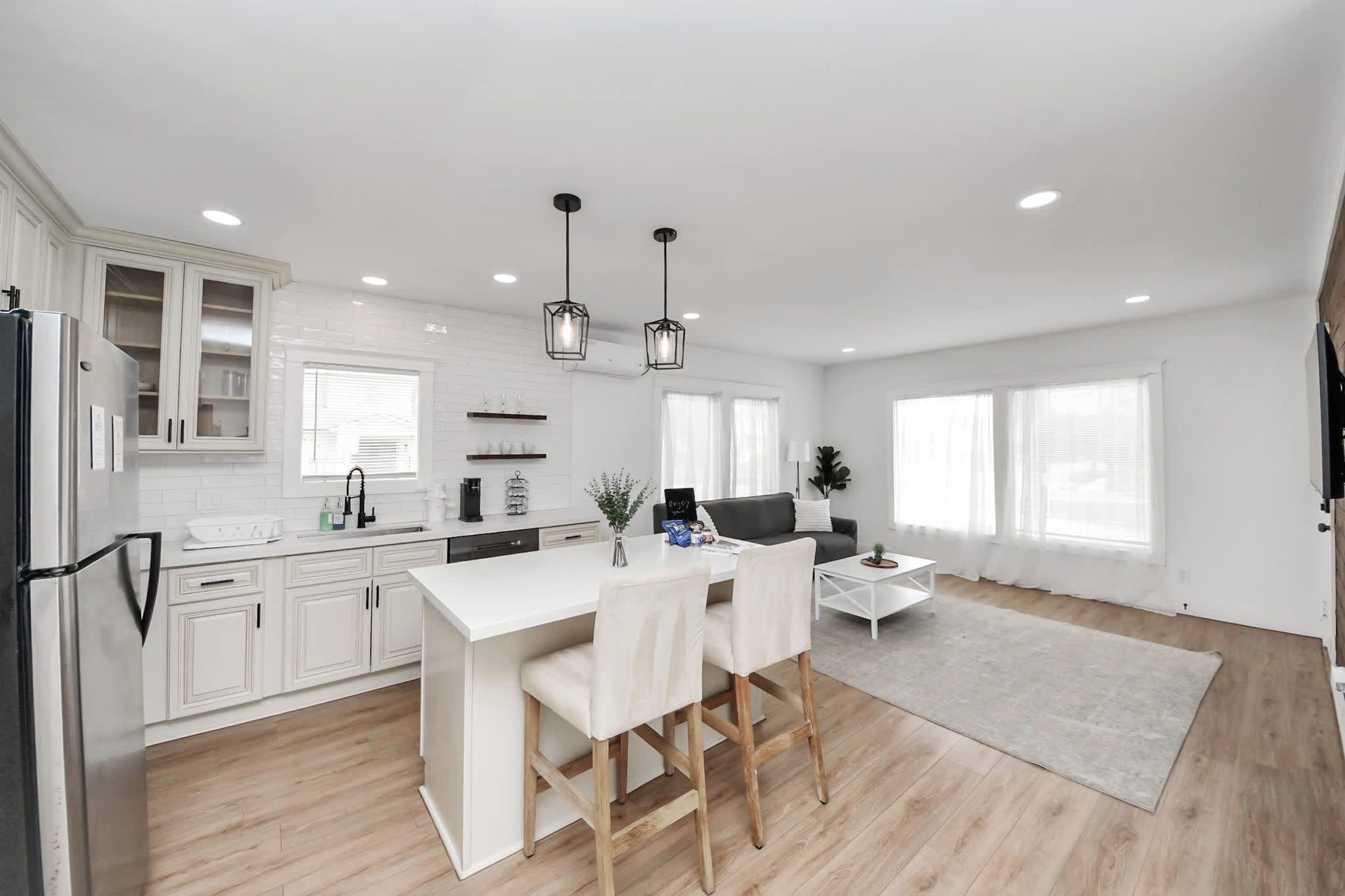 A modern kitchen with white cabinetry, a central island, and pendant lighting.