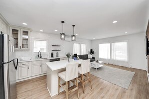 A modern kitchen with white cabinetry, a central island, and pendant lighting.
