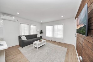 A modern living room with a sofa, coffee table, and a large window. - The Lockwood, Residence One | EaDo by the Stadiums (Houston)