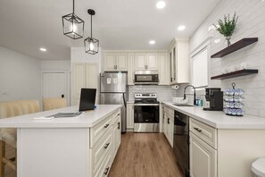 A modern kitchen with white cabinets, stainless steel appliances, and a central island.