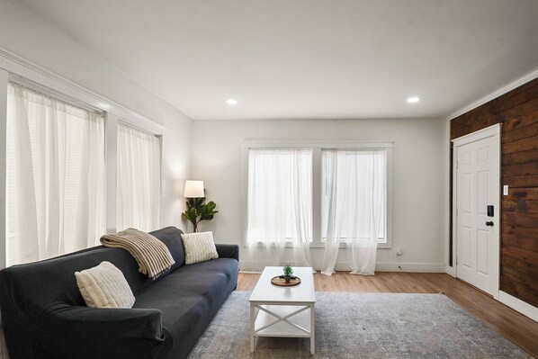 A living room with a dark sofa, a white coffee table, and a grey rug.