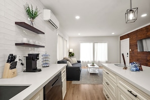 Una cocina moderna con armarios blancos, una cafetera y un bloque de cuchillos.