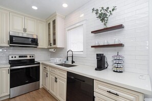 A modern kitchen with white cabinetry, stainless steel appliances, and a coffee station.