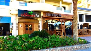 A building with a 'Havana Pub' and 'FREEDOM Coffee & More' on the ground floor. - Florenze Khamsin Hurghada Room J113 - Room 9 (Hurghada)