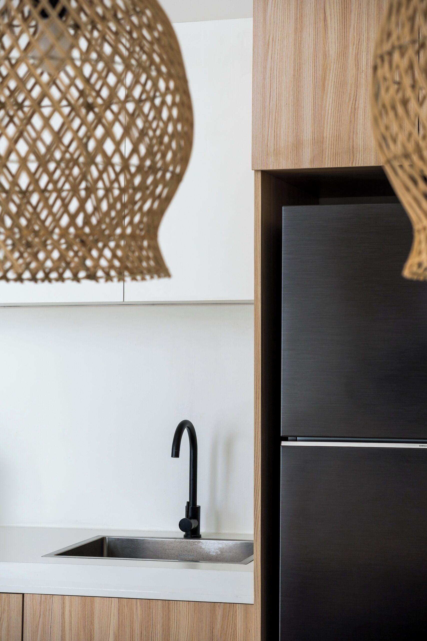Eine Küche mit einem Edelstahl-Kühlschrank, einem Waschbecken mit einem schwarzen Wasserhahn und Holzschränken.