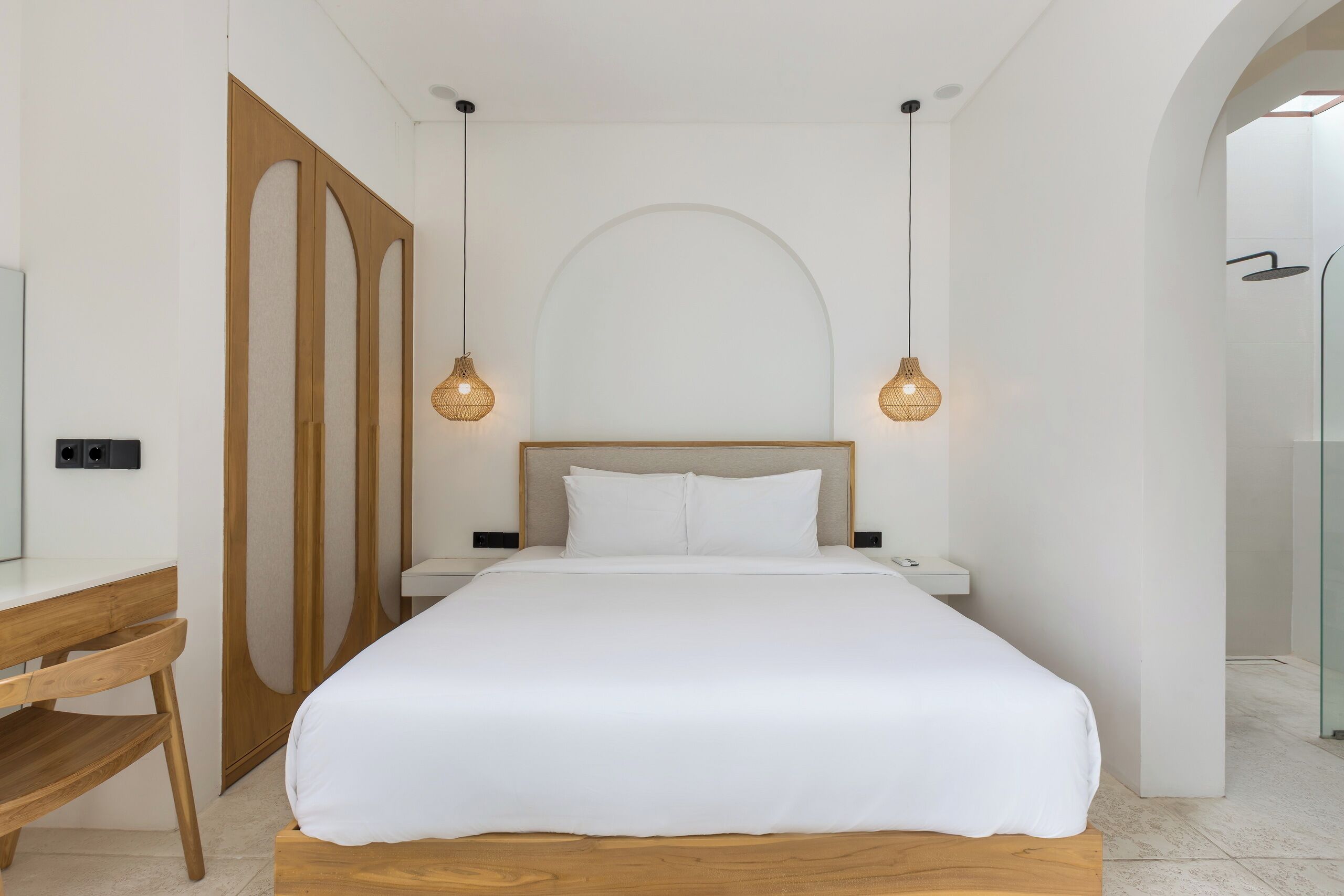 A modern bedroom with a large bed, wooden desk, and two bedside lamps.