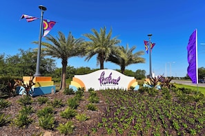 A sign for the Festival resort with palm trees and flags in the background.