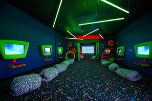 A room with multiple screens, patterned seating, and a colorful floor.