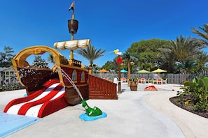 A pirate-themed play area with a ship-shaped slide, a green bucket, and a water fountain.