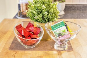 A glass bowl with red packets labeled "Godiva Masterpiece" and a glass bowl with a packet labeled "Bigelow Mint Medley Herbal Tea."