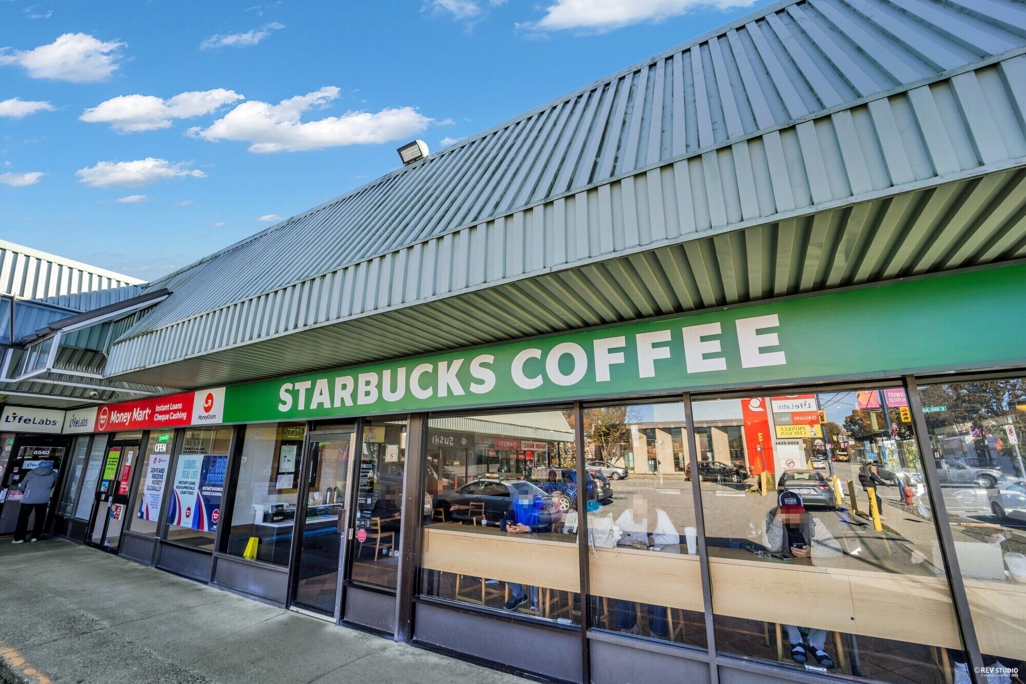 Ein Schaufenster mit einem grünen Schild, auf dem "STARBUCKS COFFEE" steht, und einem Metalldach.