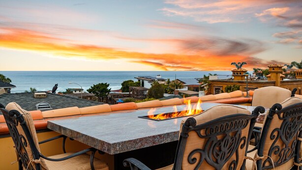 A terrace with a table and chairs, overlooking a sunset and the ocean. - Oceanview Rooftop Escape, Modern Spanish Decor (San Diego)