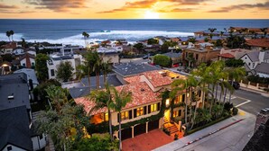 A coastal residential area with houses, palm trees, and a sunset over the ocean. - Oceanview Rooftop Escape, Modern Spanish Decor (San Diego)