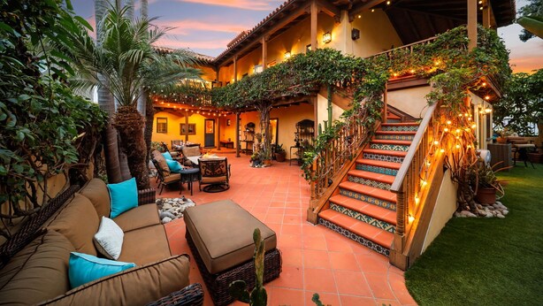 A spacious outdoor area with a covered seating area, a staircase, and a well-lit patio. - Majestic Corner Coastal Haven (San Diego)