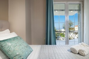 A bedroom with a bed, a view through a glass door, and a balcony with a railing. - CASA  BILA (Chania)