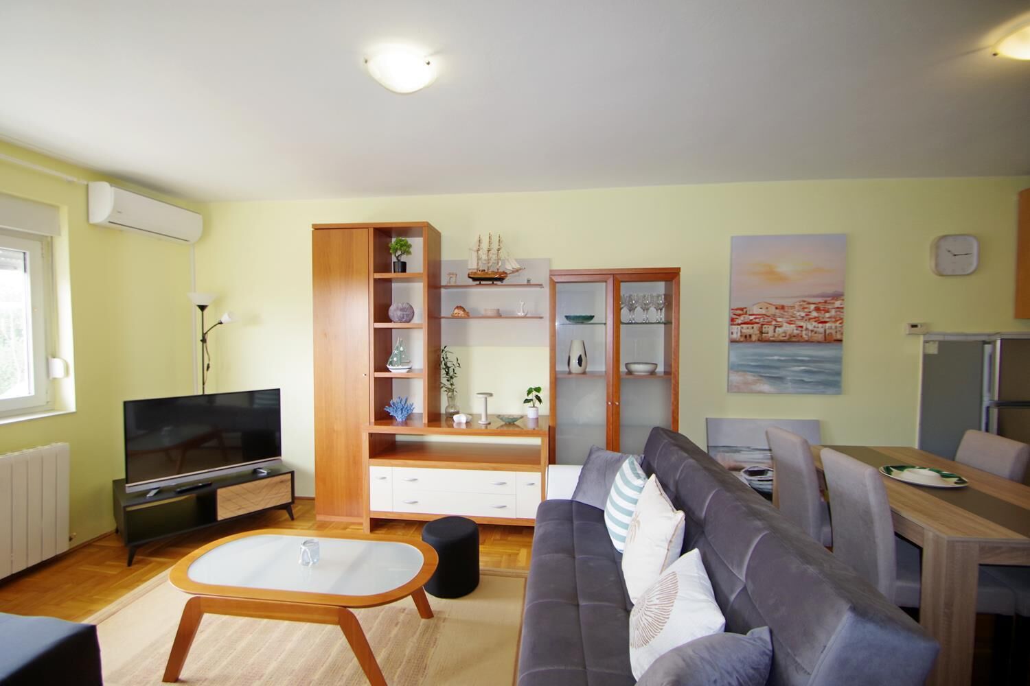 A living room with a TV, sofa, dining table, and cabinets.