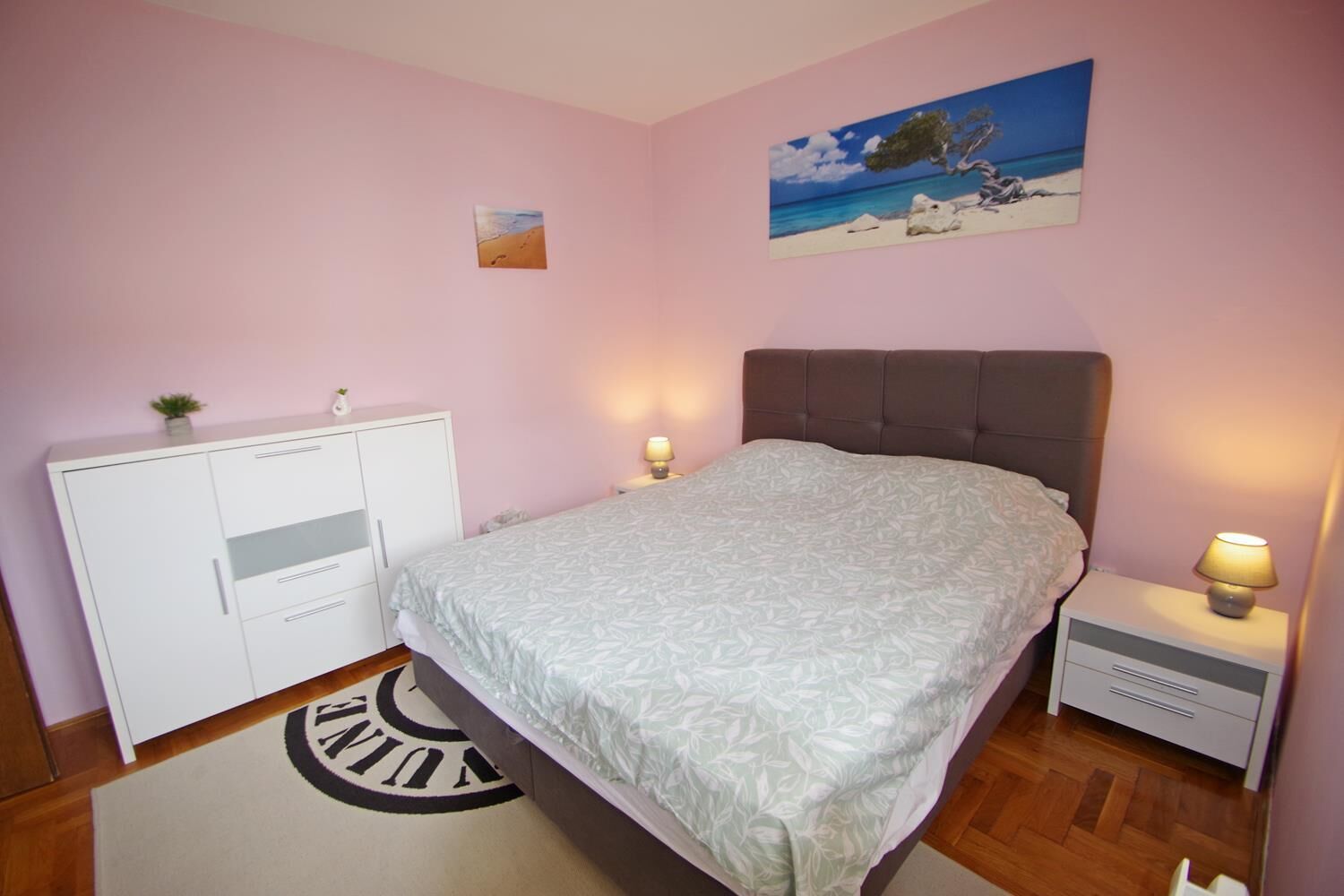 A bedroom with a bed, bedside tables, a wardrobe, and a painting on the wall.