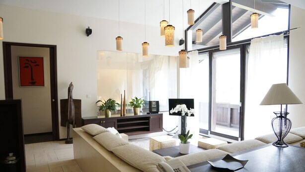 Een moderne woonkamer met een bank, een salontafel, een televisie en een groot raam met gordijnen.
