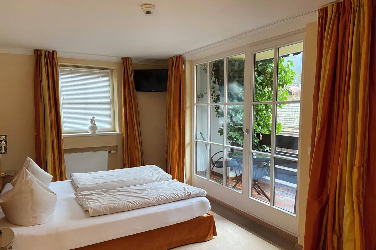 Een slaapkamer met een bed, een raam en gordijnen.