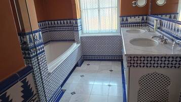 Une salle de bain avec une baignoire, deux lavabos et une fenêtre.
