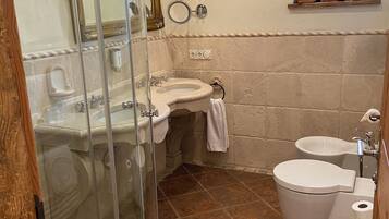 Une salle de bain avec une douche à parois de verre, un lavabo, des toilettes et un bidet.
