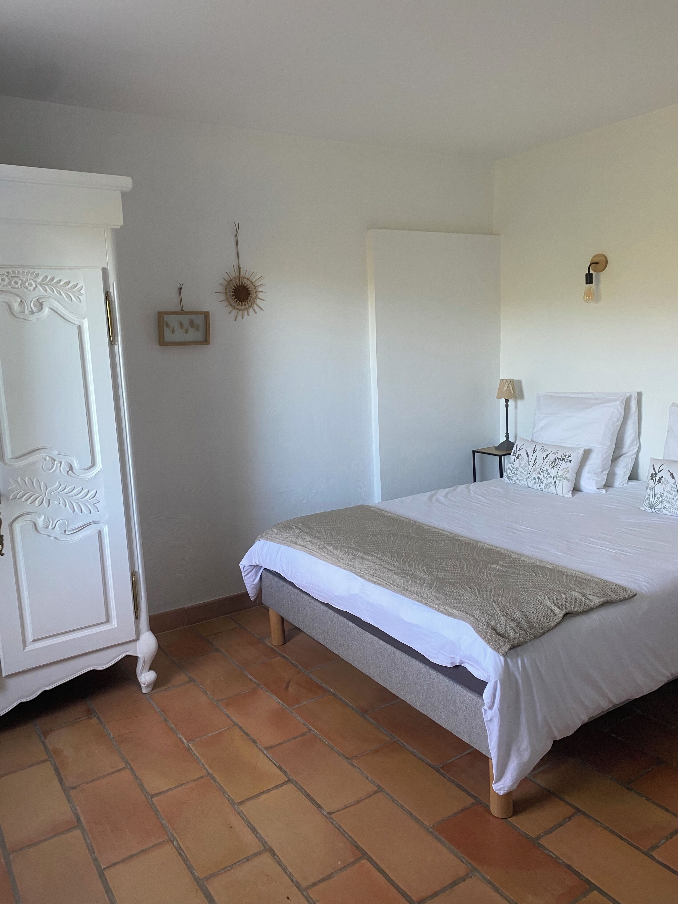 Un dormitorio con cama, armario y mesita de noche con lámpara.