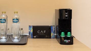 A coffee machine, two water bottles, and a box labeled 'CAF' on a table.