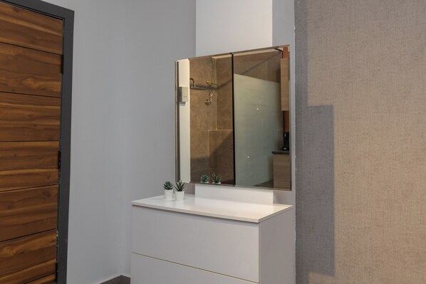 A bathroom with a wooden panel wall, a white sink with a mirror, and a glass shower enclosure. - Host Prime Boutique hotel 22 (New Cairo)