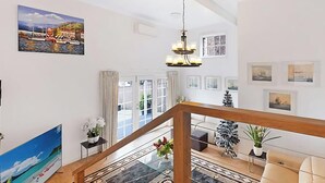 Un vaste espace de vie agrémenté d’un escalier, d’un lustre et de divers tableaux encadrés qui ornent les murs.