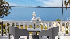 Une terrasse avec une table et des chaises, donnant sur une étendue d’eau.