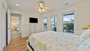 A bedroom with a bed, a ceiling fan, a TV, and a balcony with a view. - Summer Days Cooler Nights #201 - 2nd Row Dog-Friendly House in Topsail Beach! (Topsail Beach)