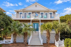 A two-story house with a balcony, a front door, and a staircase leading to the entrance.