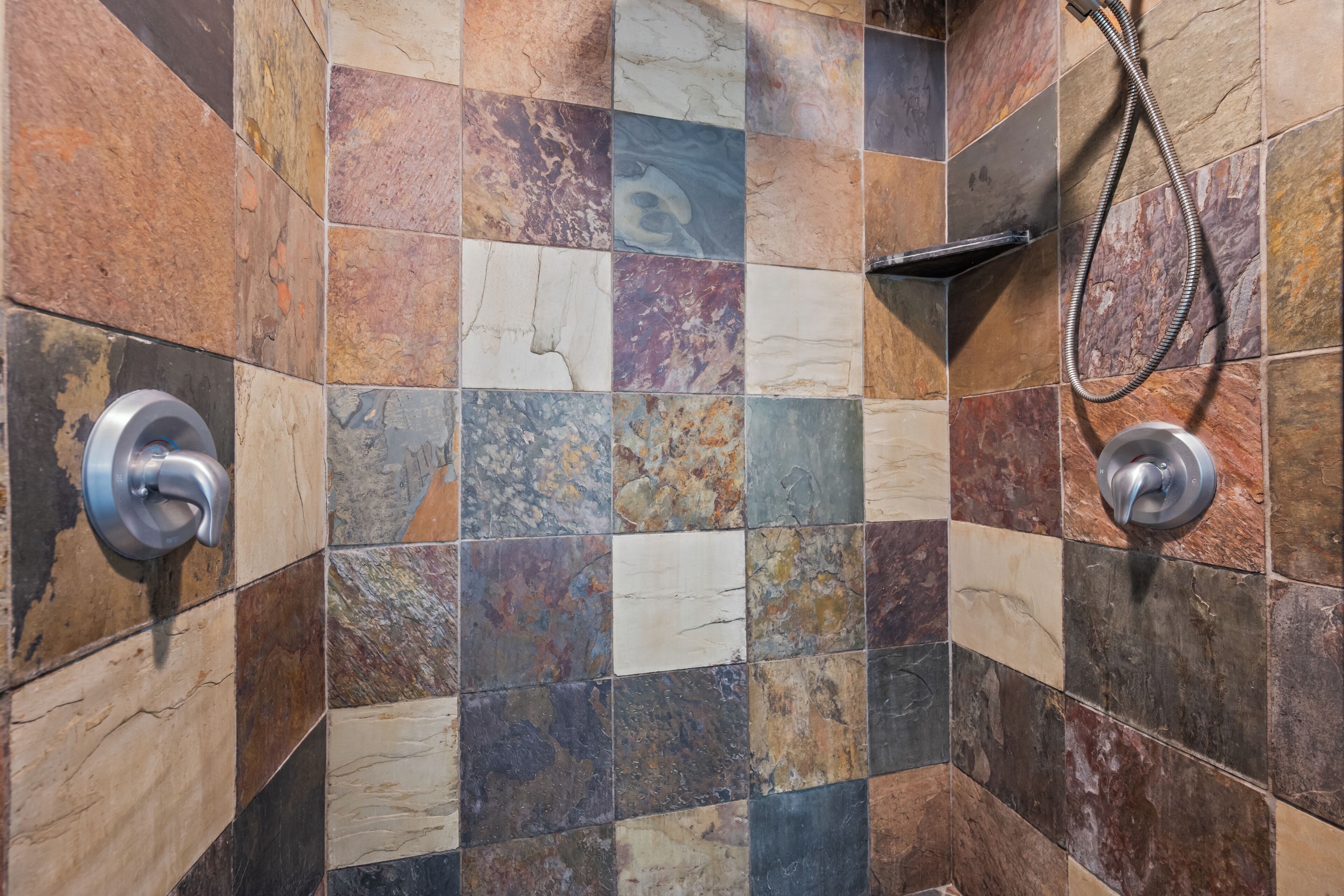 A shower area with a checkered tile wall and two showerheads.