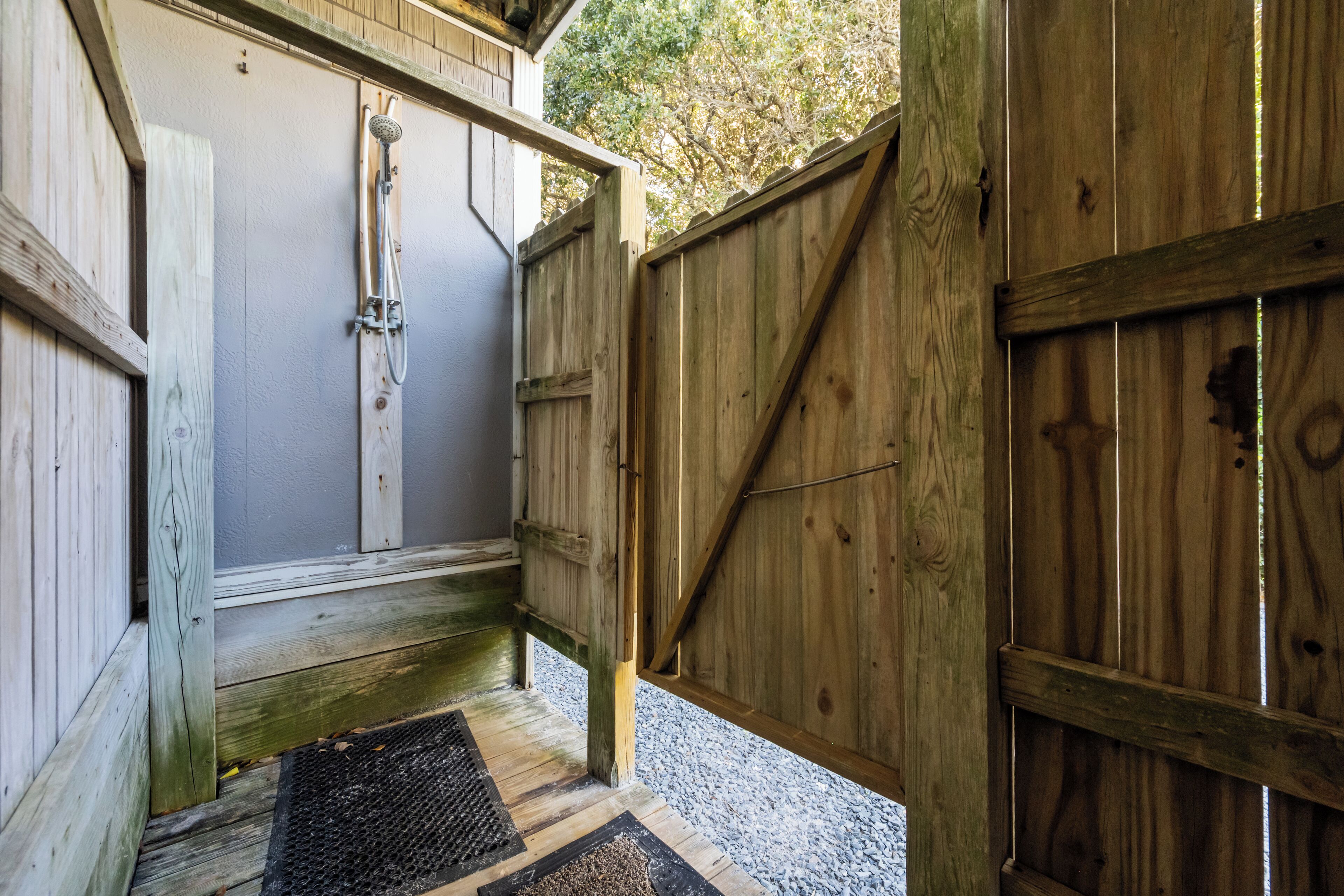 A wooden door leading to a covered outdoor area with a shower.