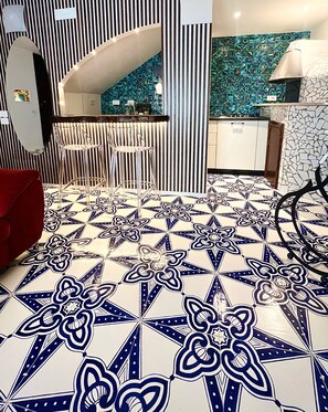 Una cocina con suelo de baldosas con motivo geométrico, pared a rayas y diseño moderno.