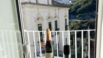 Un balcone con un tavolo, una bottiglia di vino e un bicchiere.