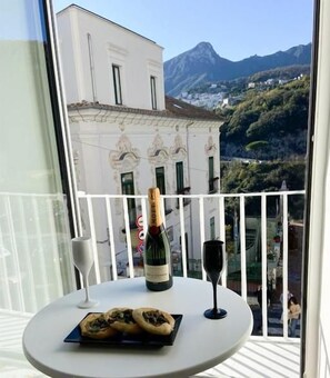 Un balcón con una mesa, una botella de vino y una copa.