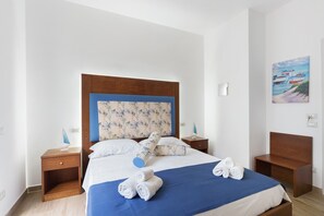 A hotel room with a bed, two nightstands, a wooden headboard, and a painting on the wall.