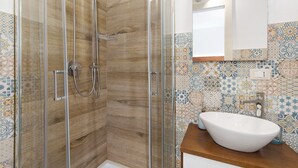 Una doccia con porta in vetro, parete in legno e pannello di copertura in piastrelle.