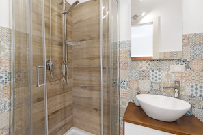 Eine Dusche mit Glastür, einer Holzvertäfelung und einer gefliesten Rückwand.