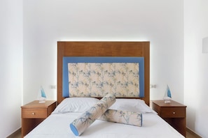 Ein Bett mit Holz-Kopfschild, zwei Nachttische und jeweils ein Segelboot-Dekoration auf jedem Tisch.