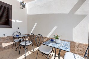 Eine Terrasse im Freien mit Tisch und Stühlen, einem Blumentopf und einer Steinmauer.